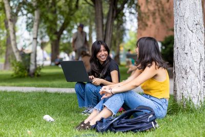 Two students study together outside on the lawn.
