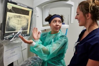 Two dental hygienist students look at an screen displaying a dental x-ray.